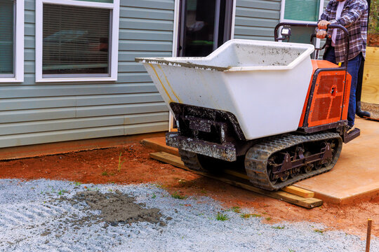 Construction worker operates tracked dumper to fresh wet concrete for abuilding project