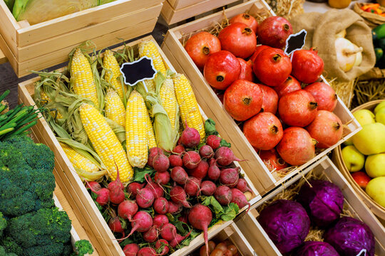 Fresh produce is displayed in wooden crates at farmers market in autumn, various fruits vegetables.
