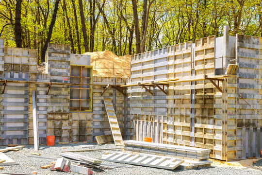 Concrete forms are being assembled at construction site surrounded by trees