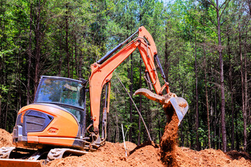 Excavator is working in forested area, moving dirt during digging trenches construction project