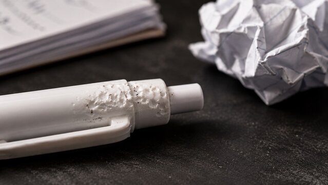 Close-up of white correction tape resting on a dark desk next to crumpled pieces of paper