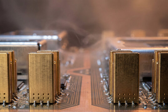 Close-up of electronic circuit board with metal shielding components and rising vapor