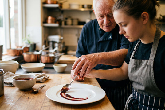 Chef cuisinier transmettant son savoir &agrave; une jeune apprentie pour le dressage