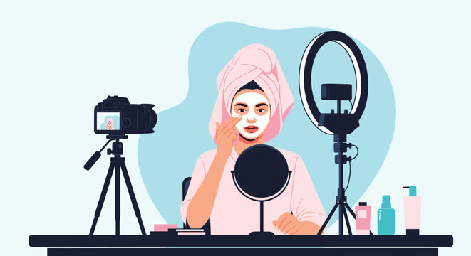 Beauty influencer wearing a towel applies a face mask while recording a video for her followers using professional camera and lighting gear.