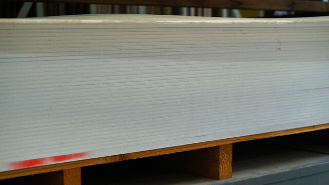 Neat stack of drywall plasterboard sheets on a wooden pallet