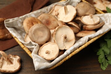Fototapeta premium Raw shiitake mushrooms in wicker basket on wooden table, closeup