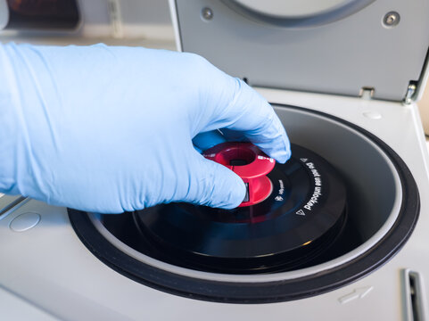 Brussels, Belgium. Laboratory technician securing a centrifuge rotor during DNA extraction workflow