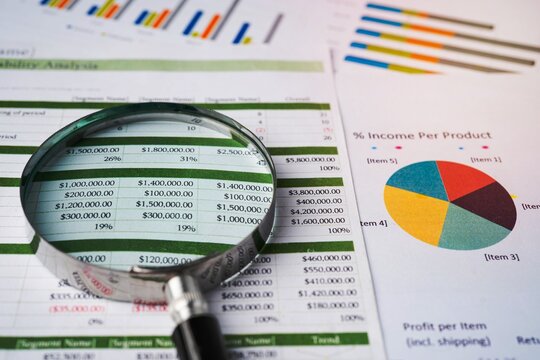 Magnifying glass focused on financial statements and pie chart analysis with magnifying business analysis accounting financial
