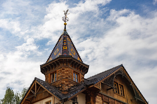 Beautiful historic wooden building tower with colorful tiled roof against blue sky in Ukraine