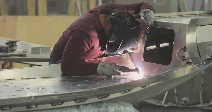 Close-up of welding an aluminum boat hull or aluminum alloys. Production of an aluminum hull for a boat. Welding process in the shop. Shipyard. Welders weld a RIB boat hull.