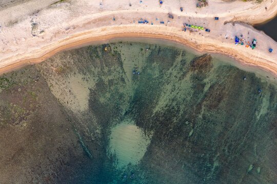 Aerial view of Bai Hom beach featuring clear turquoise water, sandy shoreline, and scattered beachgoers in Vinh Hai, Khanh Hoa, Vietnam.