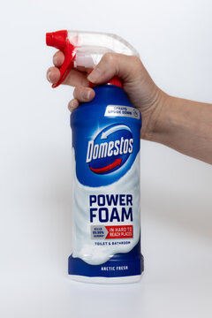 Human hand holding Domestos Power Foam cleaner spray bottle isolated on white background