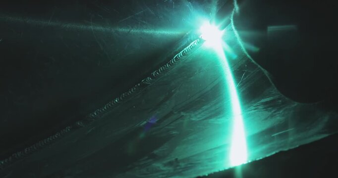 Close-up of welding an aluminum boat hull or aluminum alloys. Green beam from welding aluminum parts. Production of an aluminum hull for a boat. Welding process. Close-up.  