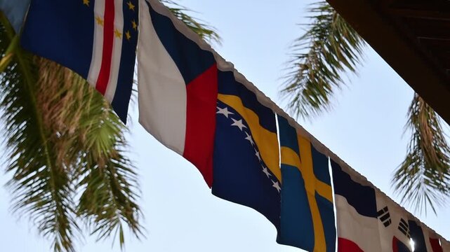 National flags gently sway in tropical breeze beneath palm trees, symbolizing international unity, travel and global events.
