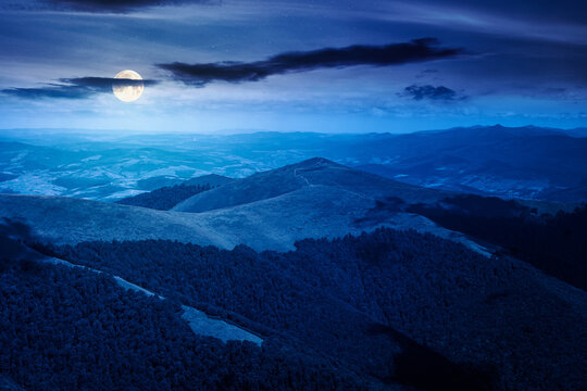 mysterious mountain landscape in summer at night. travel ukraine background. full moon over rolling hill in dappled light. scenic view of borzhava ridge. carpathian mountain scenery