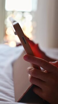 Child plays mobile game on touchscreen tablet while relaxing on bed in softly lit room during quiet indoor leisure time.