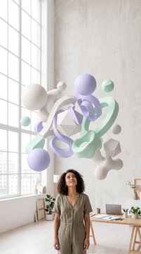 Young woman looking up at floating 3D abstract geometric shapes in a bright modern studio