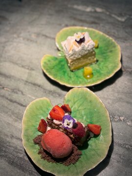 Duas sobremesas gourmet servidas em pratos de cer&acirc;mica verde, decora&ccedil;&atilde;o elegante e apresenta&ccedil;&atilde;o sofisticada.