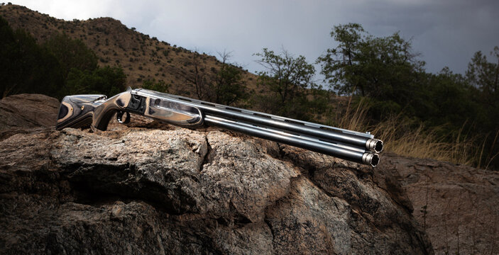 Double barreled 12 gauge shotgun on a boulder on an overcast day