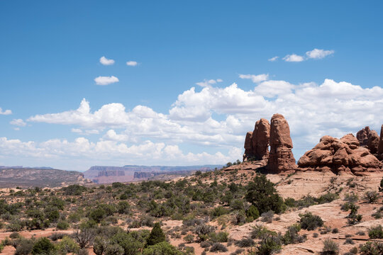 Long shot of Arches National Park in Moab, Utah in southern Utah. Vast red rock landscape with blue sky and tall rock formations in the middle ground.  Popular travel destination in America.
