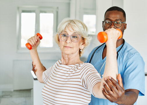 Doctor or nurse or physiotherapist caregiver exercise with senior woman at clinic or nursing home