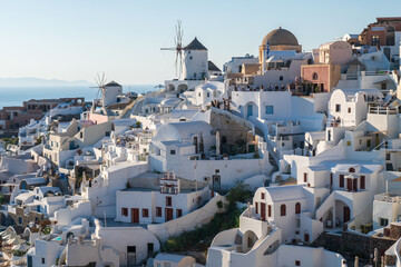 Panoramic view of Oia’s white buildings, blue sea, and warm sunset light on Santorini island, Greece. © Andrei Tomas
