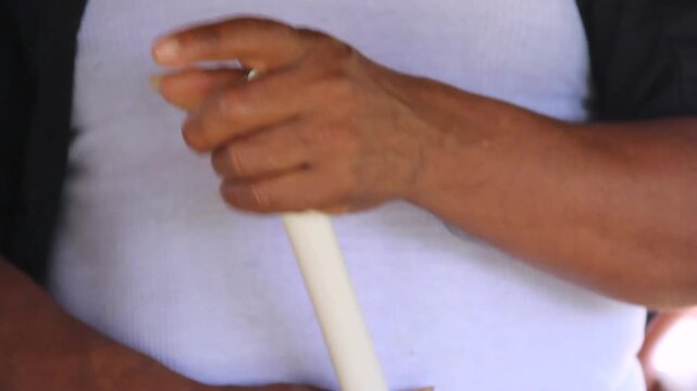 Close-up of hands holding a simple flute. Fingers gently press holes to play music. Calm, focused expression suggests quiet enjoyment. Ideal for cultural, musical, or heritage projects. Lamas, Tarapot