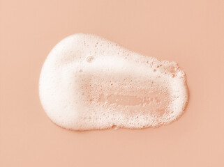 Fototapeta premium White skincare cleansing foam on light peach background