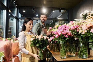 Couple works together arranging roses and other blooms in their vibrant florist shop.