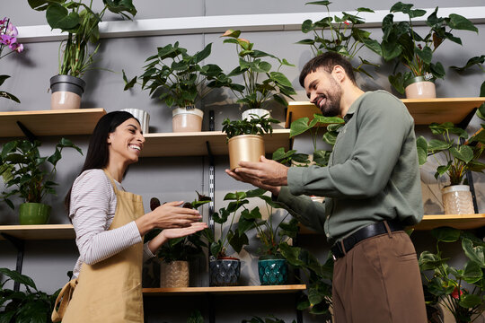 A skilled florist shares her passion with a client while surrounded by lush greenery.