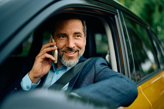 Happy entrepreneur talking on the phone while driving a car.