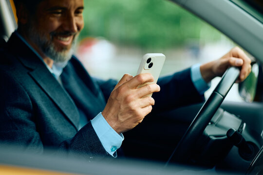 Close up of businessman using cell phone while commuting to work by car.