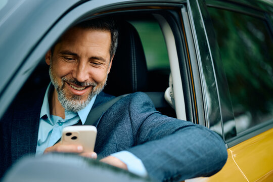 Happy businessman using navigation software on smart phone while driving.