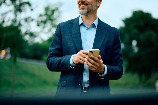 Close up of businessman using cell phone in the park.