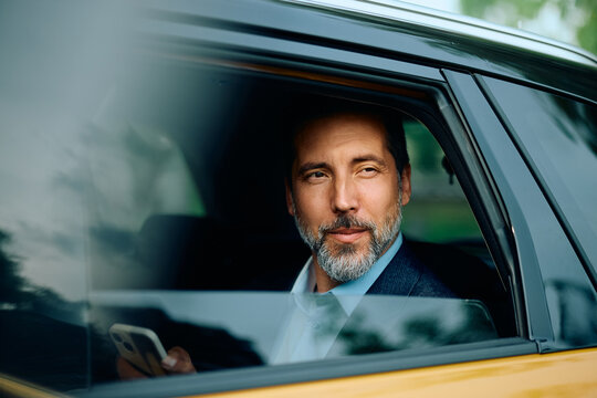 Pensive businessman commuting to work on backseat of a car.