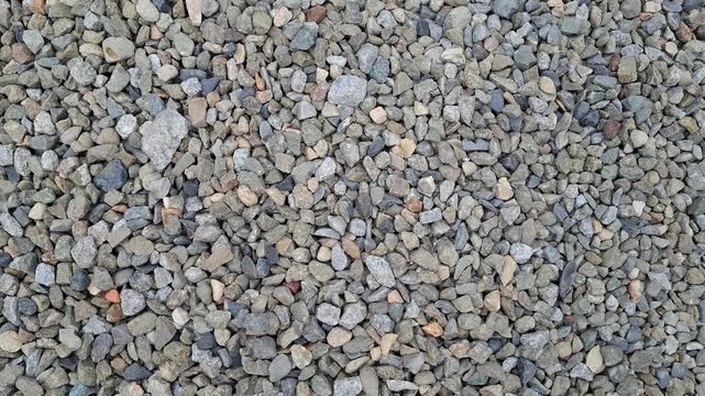 Textured grey gravel surface composed of small crushed stones. Clean background texture, dense layer of natural granite pebbles, perfect for construction, landscaping, and abstract designs