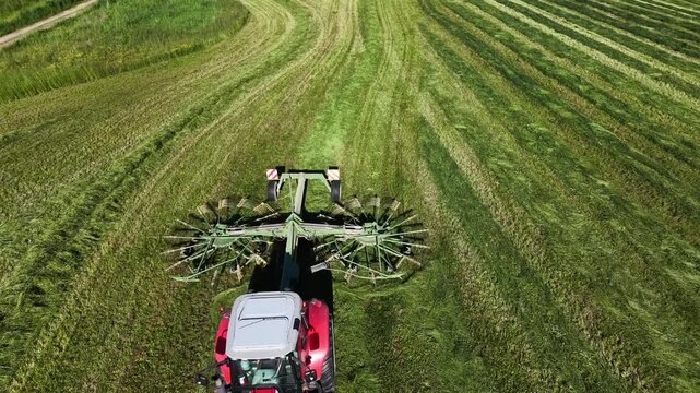 A tractor is pulling a hay rake in the field