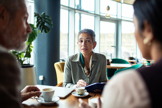 Mature businesswoman meeting with colleagues in cafe