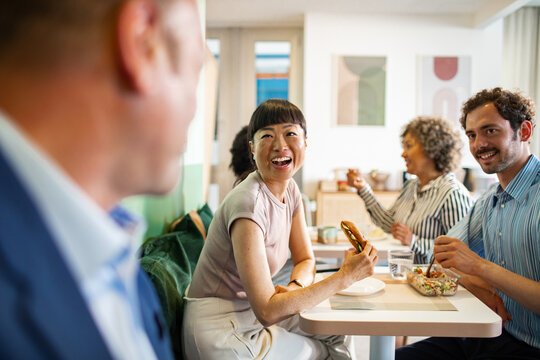 Group of coworkers eating lunch in office cafeteria