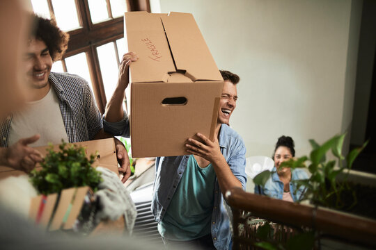Friends carrying moving boxes in apartment stairwell