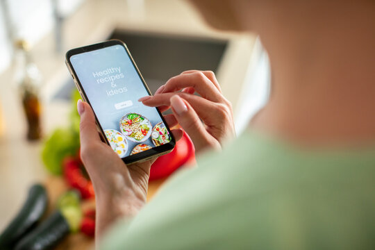 Person using healthy recipe app in home kitchen