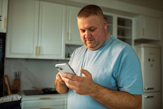 Middle aged man using smartphone in home kitchen