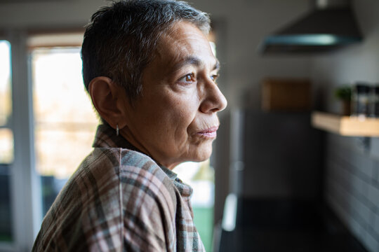 Thoughtful senior woman gazing out in home kitchen