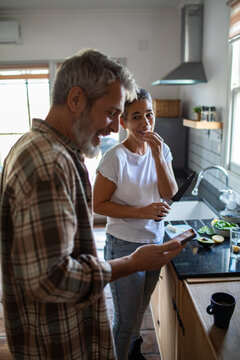 Smiling mature couple cooking together in home kitchen