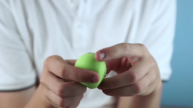 teenager playing with soft green dumpling antistress toy squeezing squishy character for relaxation, close up shot, bright atmosphere, concept of stress relief, sensory fidget game, hobby