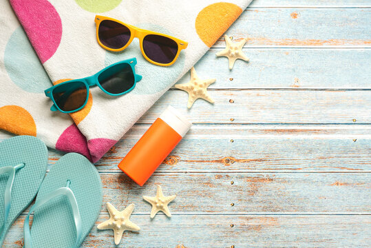 Top view of bottle of sunscreen,sunglasses,flip flops and beach towel with space for text