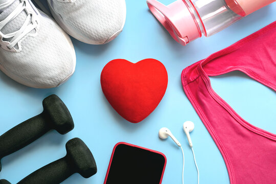Top view of fitness accessories,mobile phone and headphones with a red heart in the center. Sport and fitness concept