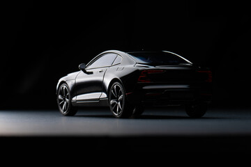 Naklejka premium Rear three quarter view of glossy performance coupe model in moody studio scene.