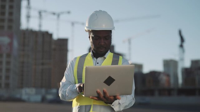 Large construction site with new modern buildings, foreman using laptop. Architect controlling project implementation, modern technology and innovation in architecture, office district in city center