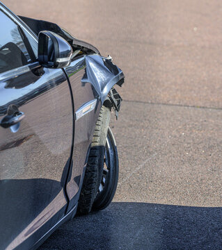 Black car with crushed front fender after collision.